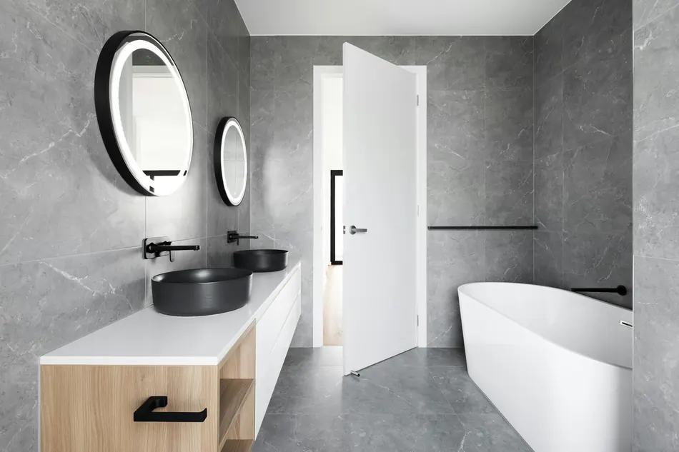 A stone-clad bathroom with wall-mounted tapware and a freestanding bath.