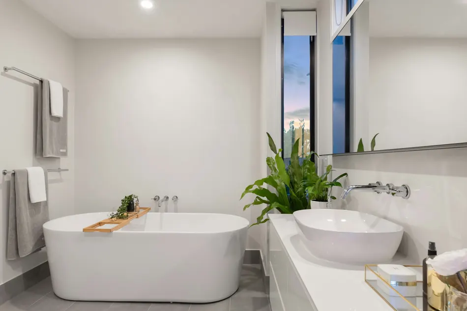 A freestanding tub beside a glazed wall with a wall-mounted filler.