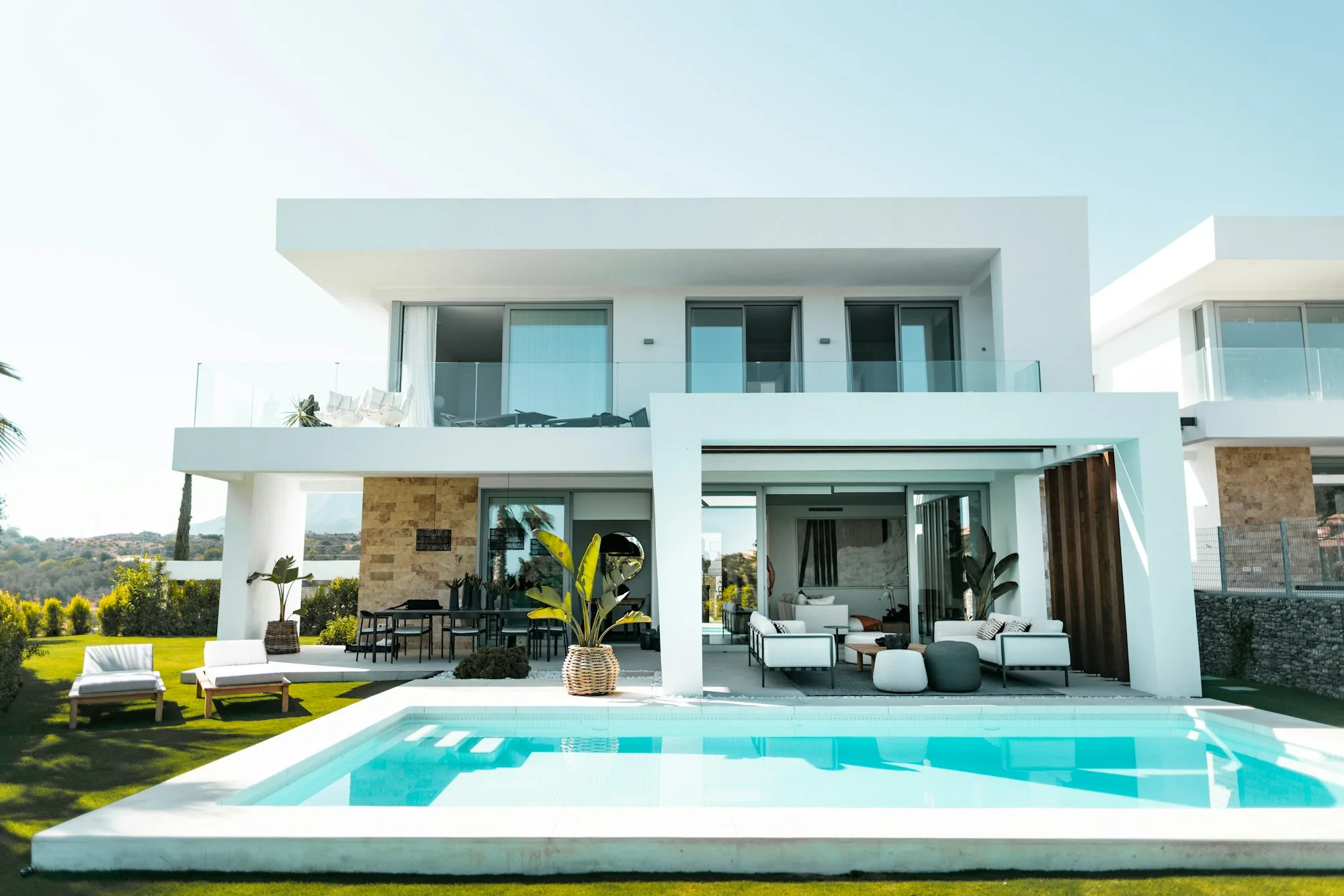 A white contemporary villa with a pool and mature planting, typical of the coastal Orange County homes served.